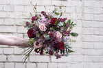 A mixed hand tied bouquet with red and pink roses and other pink flowers for Valentines Day